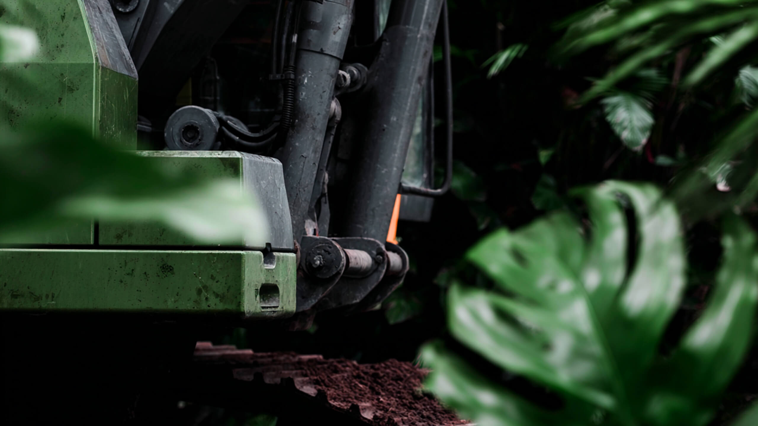 Detail eines Minibaggers beim Aushub, umgeben von Blättern – präzise Technik für Erdarbeiten